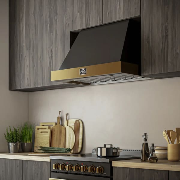 Modern kitchen interior featuring the Forno Vittorio 36-Inch Wall Mount Range Hood with antique brass trim, installed above a stainless steel cooktop. The hood blends seamlessly with white cabinetry and upscale decor, showcasing both functionality and elegant design.