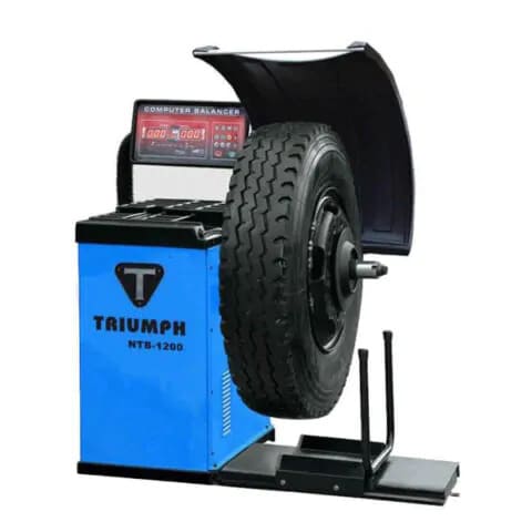 Triumph NTB-1200 Electronic Truck Wheel Balancer unit with protective cover and control panel for heavy-duty and passenger wheel balancing.