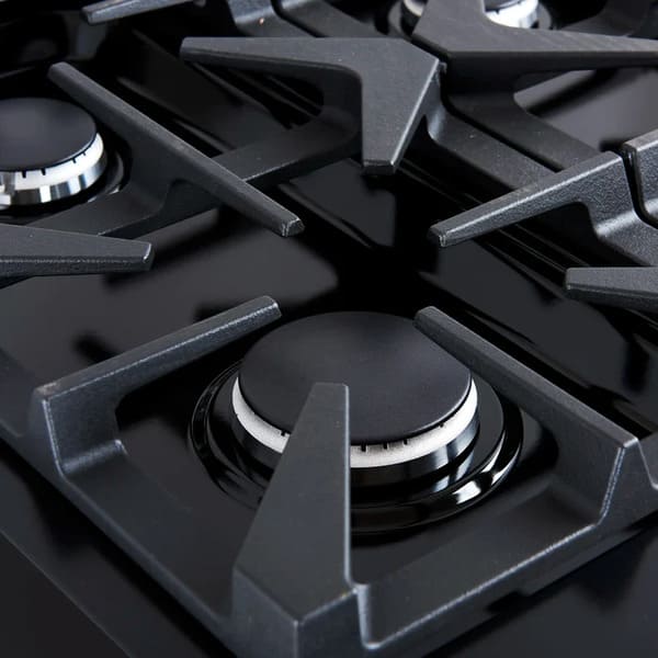 Close-up of a brass burner on the FORNO Antico 36-Inch Gas Range in black, showing precision flame ports, durable cast iron grate, and sleek black stainless steel surrounding the burner.