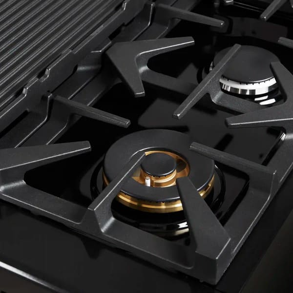 Close-up of a brass burner on the Forno Antico 48-Inch Gas Range, highlighting precision flame ports, durable cast iron grates, and a polished stainless steel cooktop surface.